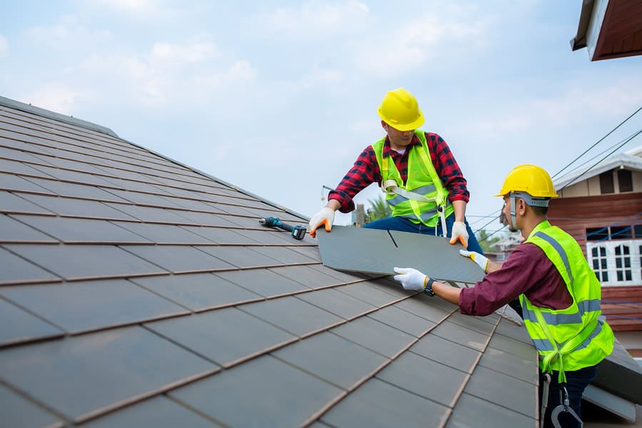 Roofing crew installing asphalt shingles on a residential roof
