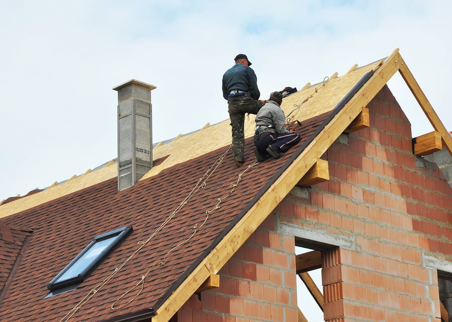 Roofing crew working near a roof ridge